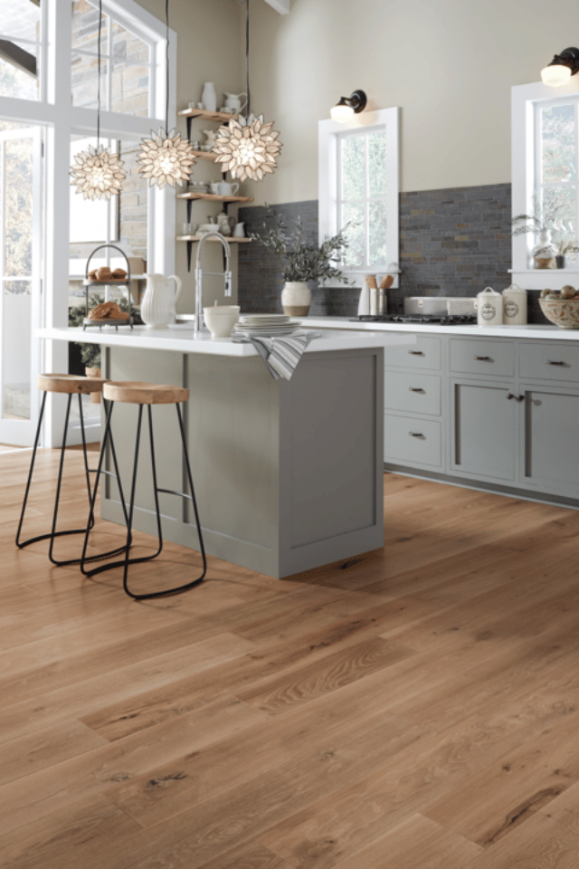 warm toned hardwood flooring in kitchen with grey kitchen island and stools